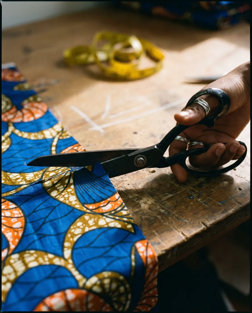 Scissors cutting printed ankara on a tailor's table