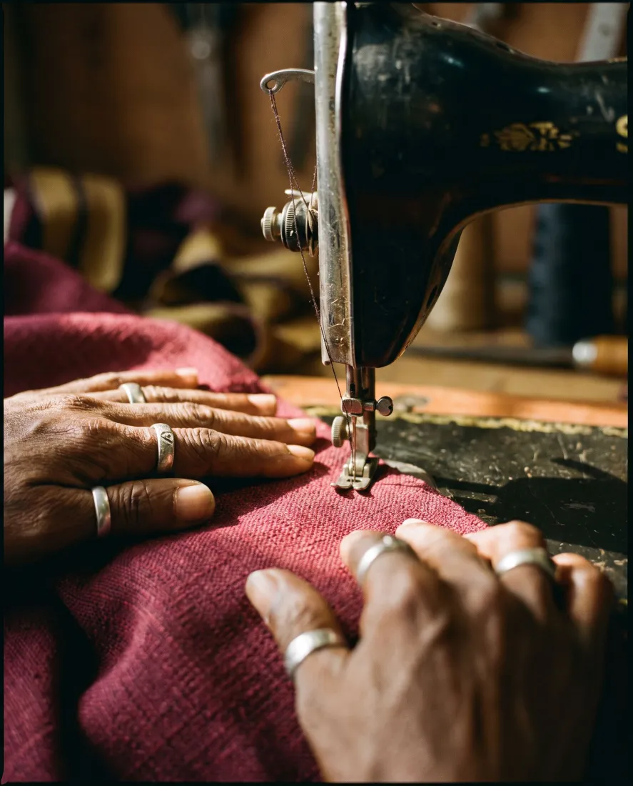 A tailor's hands feeding aso oke under the needle